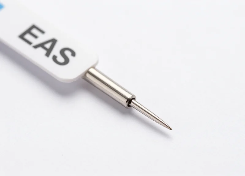Macro photography of an ultra-thin security tag needle with a polished metallic finish.