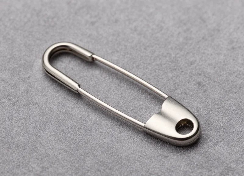 Macro shot of a smooth security pin resting on delicate suede fabric without leaving marks.