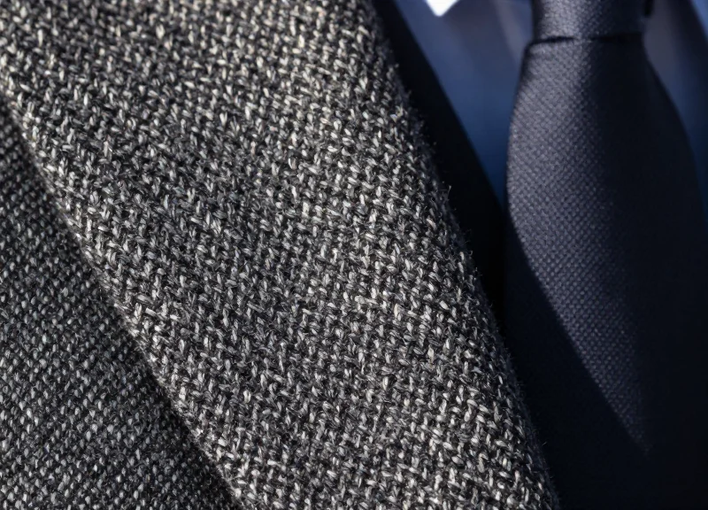 Macro shot of high-quality menswear fabric textures showing intricate weave patterns.