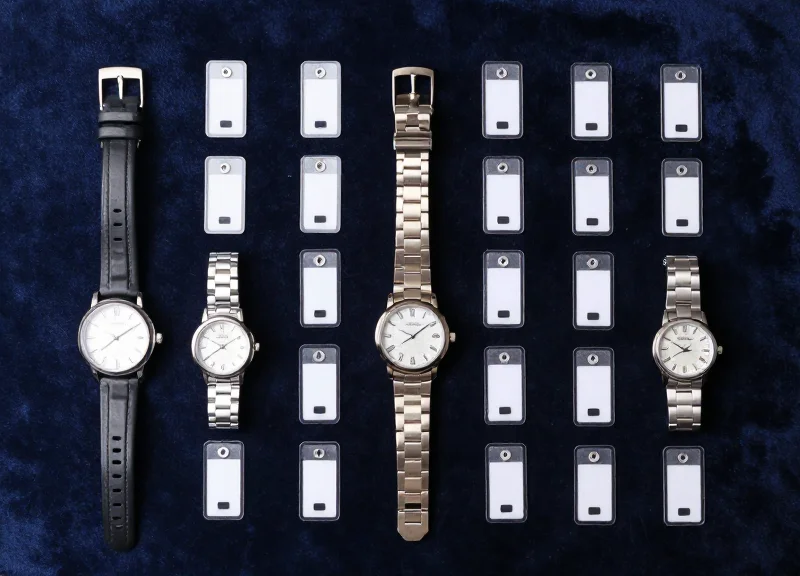 Neatly organized collection of luxury watches and RFID security tags on a dark velvet surface.