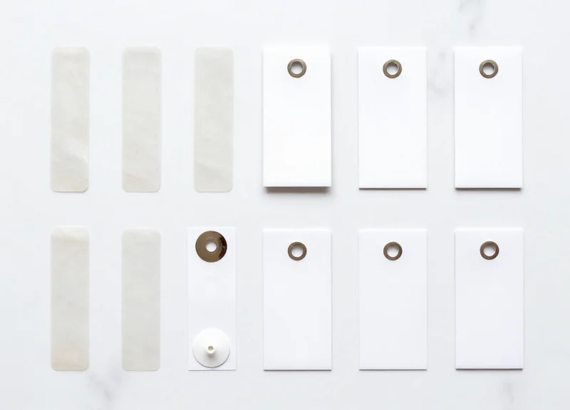An organized collection of various book security tags, adhesive strips, and hard tags laid out on a white surface.