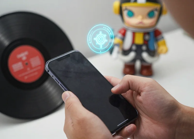 A close-up of a person using a smartphone to scan a designer toy for authentication.