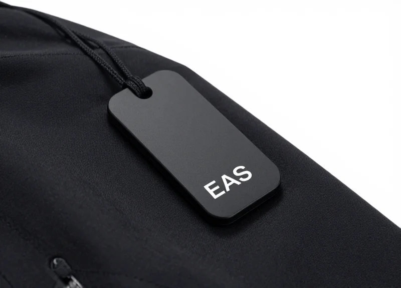 A sleek black non-damaging security tag mounted on a high-value sports jacket collar.