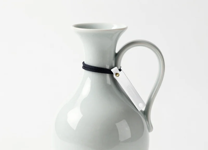 A fragile ceramic vase with a small, discreet security tag attached.