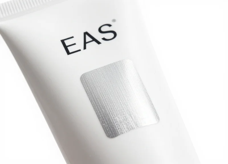 Close-up of a thin EAS soft label applied to the back of a cosmetic tube