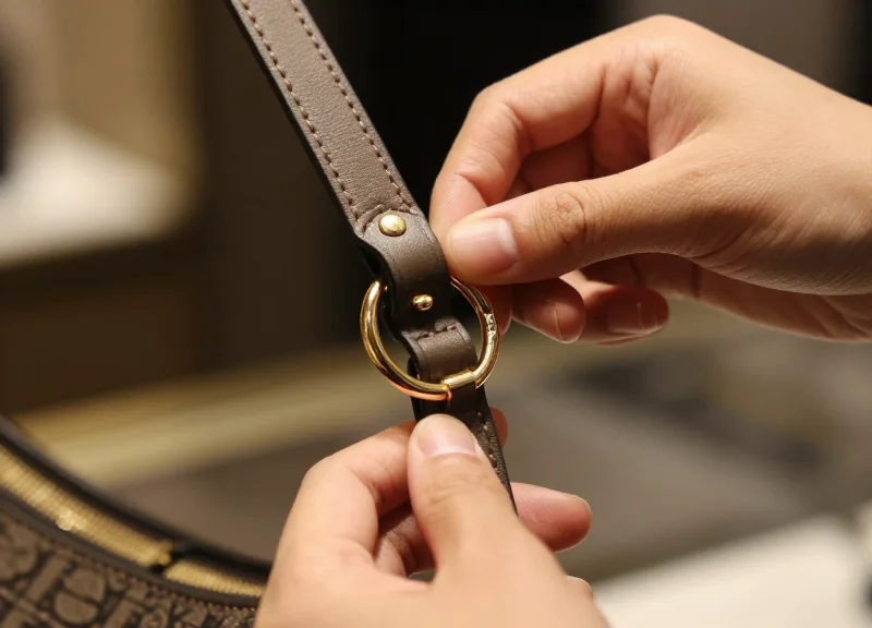 Close-up of a security tag being secured to a luxury handbag's metal hardware.