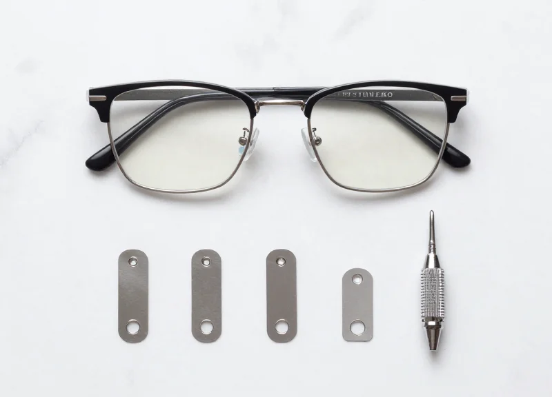 Flat lay of luxury glasses, slim EAS tags, and a precision applicator tool