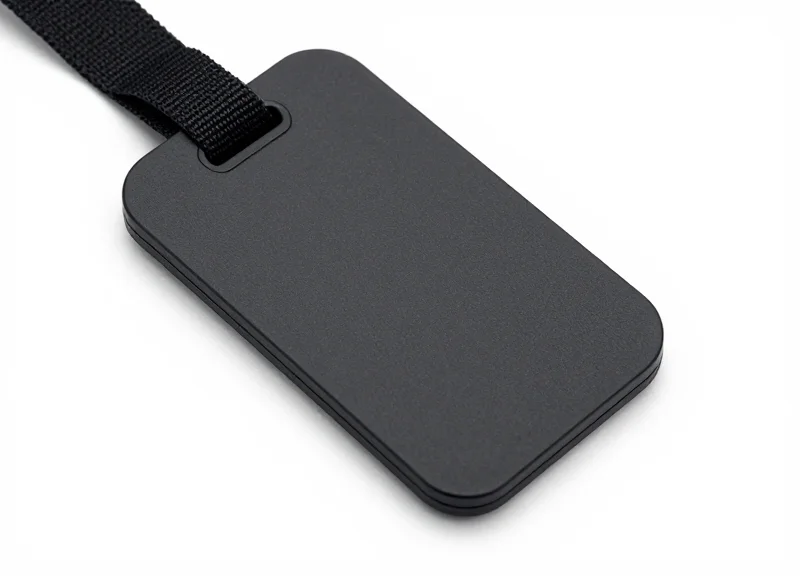 Close-up of a modern matte black self-alarming security tag attached to a luxury fabric.