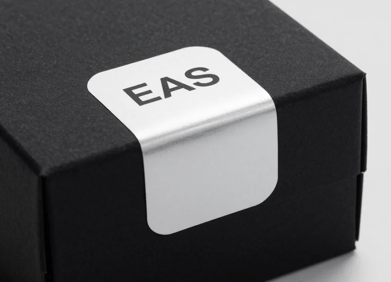 A high-end close-up shot of a sleek, blank EAS security label applied to a luxury matte-finish gift box, emphasizing a clean and residue-free surface.