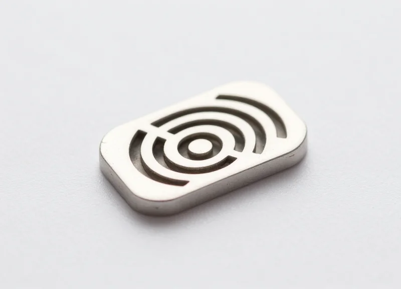 A tiny, miniature anti-metal RFID tag compared to the size of a finger.