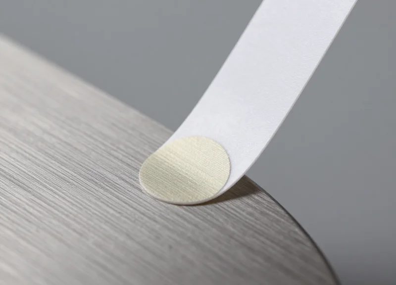 Macro view of an RFID tag adhesive backing being applied to a curved metal surface.