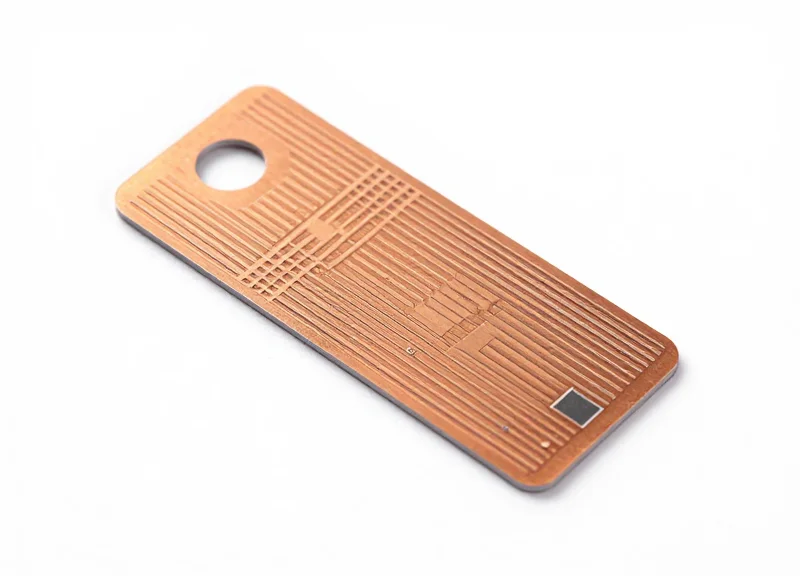 A high-detail shot of a flexible RFID tag inlay showing the copper antenna pattern on a white background.