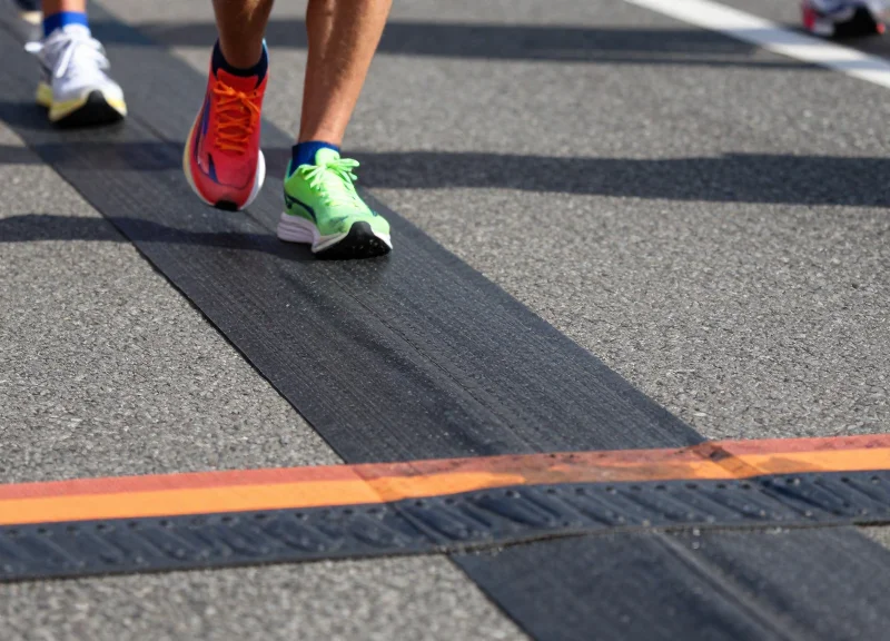Close-up of marathon runners' feet crossing a professional RFID timing mat at a race finish line.