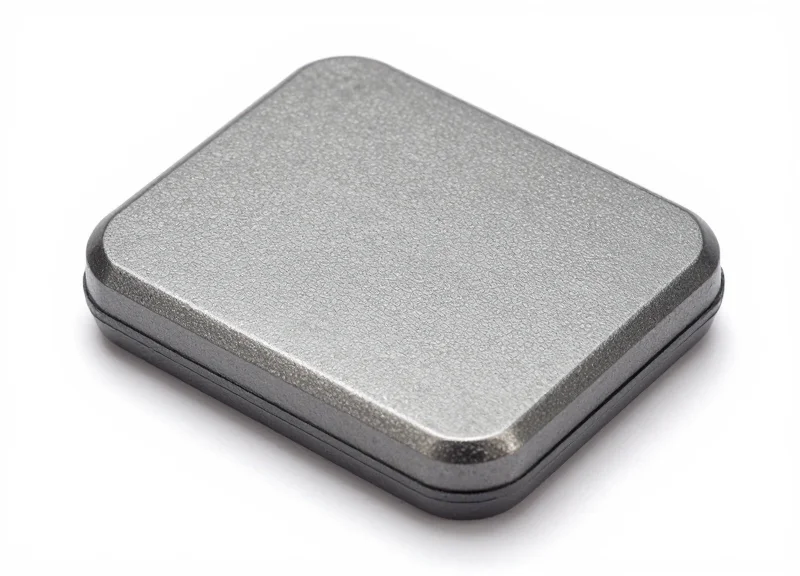 Studio shot of a flat, slim, ruggedized under-carpet RFID antenna showing its durable outer casing.