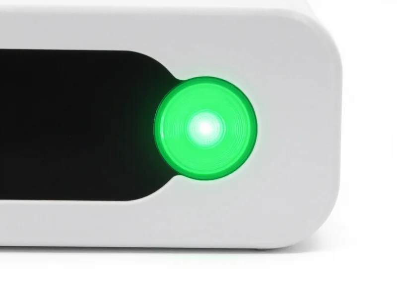 Close-up of an electronic shelf label with a bright green LED light illuminated on its top corner.